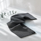 Exfoliačný uterák Kōji Face Towel rozvlnený na svetlom pozadí